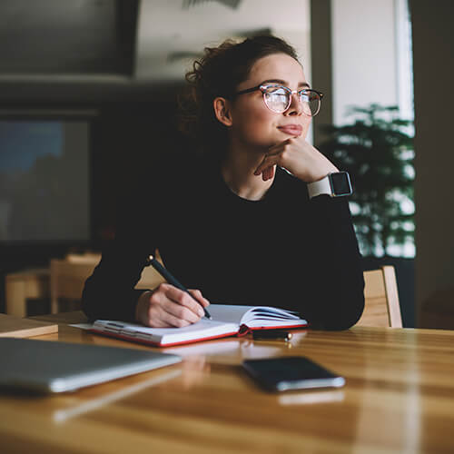 Woman thinking at a desk with a notebook