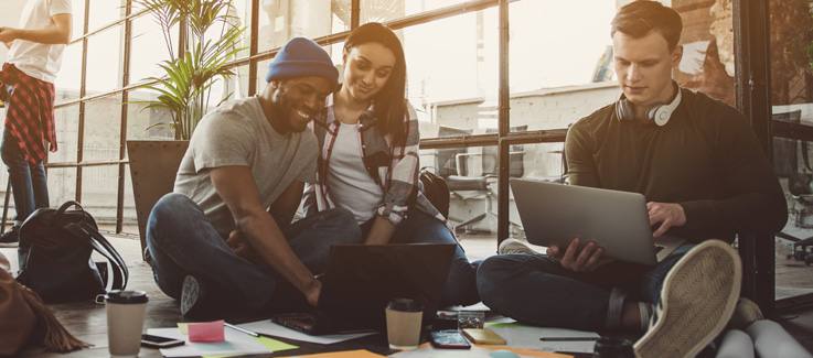 Image of three young adults using laptops.