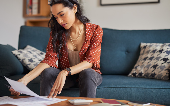 Woman looking at paper student loan statements.