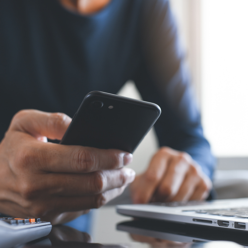 Hands holding phone next to computer